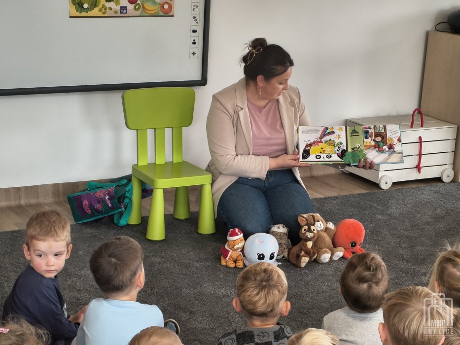 Biblioteka Gorlice, Cała Polska czyta dzieciom bibliotekarka prezentuje dzieciom ilustracje w książce
